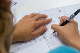 Bird's Eye view of a child drawing a comic. The comic itself is blurry.