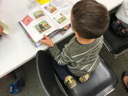 Bird's Eye view of a child sitting at a table with an open book. The book has colorful pictures