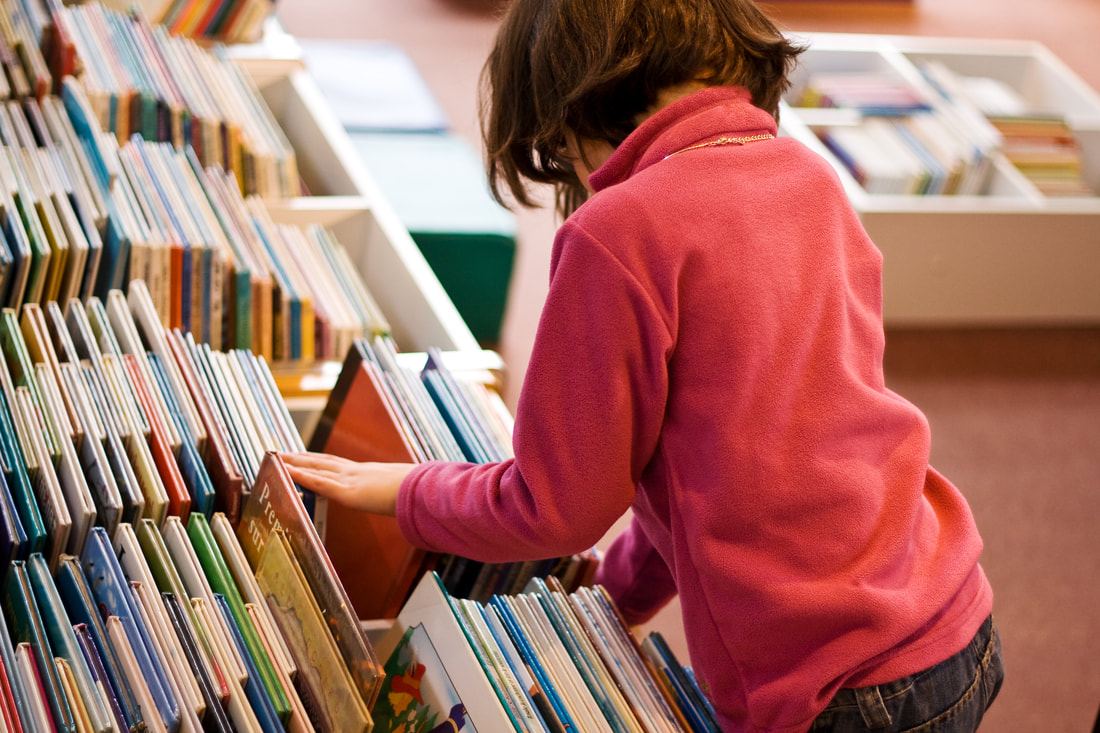 Child browsing for books in a book bin